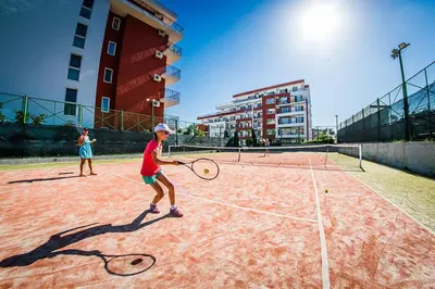 two children playing tennis on a tennis court at 1kk ve Sveti Vlas in Nesebar