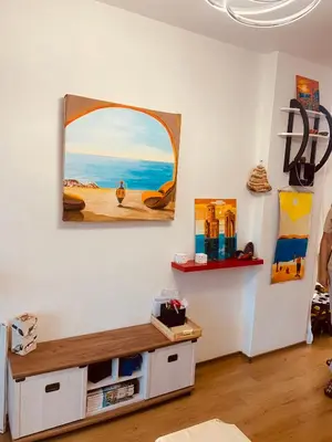a living room with a table and a painting on the wall at Студия Мир Авангарда in Sunny Beach