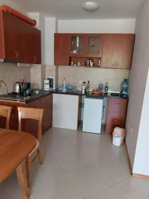 a kitchen with wooden cabinets and a table and a table and a table at Просторная квартира в популярном комплексе in Sunny Beach