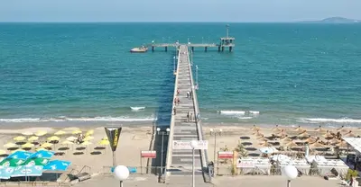 a pier over the beach with umbrellas and the ocean at Luxury Apartment in Cascadas Family Resort Sunny Beach in Sunny Beach