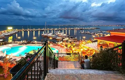 a man is taking a picture of a marina at night at Luxury Apartment in Cascadas Family Resort Sunny Beach in Sunny Beach