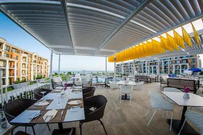 a restaurant with tables and chairs on a balcony at Premier Fort Cuisine - Full Board in Sunny Beach