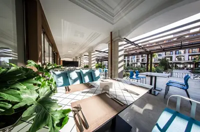 an outdoor patio with blue chairs and tables and plants at Premier Fort Cuisine - Full Board in Sunny Beach
