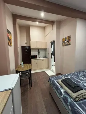a bedroom with a bed and a table and a kitchen at GRAND STUDIO SEA GARDEN - top center in Burgas City