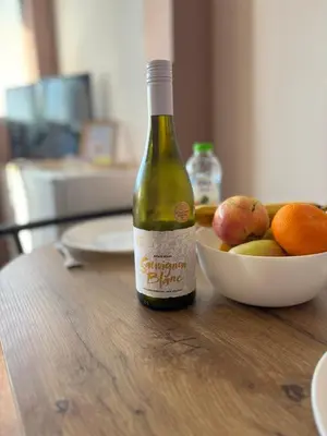 a bottle of wine sitting on a table with a bowl of fruit at GRAND STUDIO SEA GARDEN - top center in Burgas City
