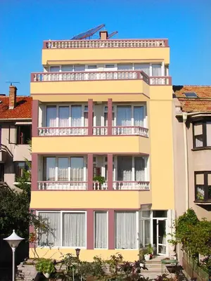 a tall yellow building with a balcony at Hotel Bobchev in Sozopol