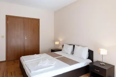 a bedroom with a large bed with a wooden cabinet at Midia Holiday Apartments in Aheloy