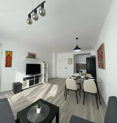 a white living room with a table and chairs at Prestige Apartment 1 in Burgas City