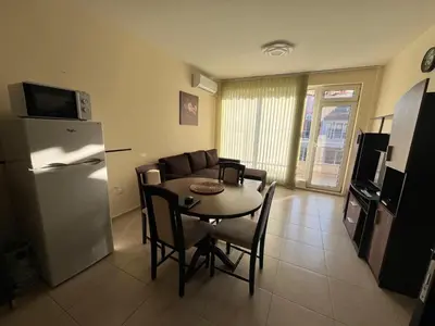 a living room with a table and a refrigerator at Sunset Apartment Pomorie in Pomorie