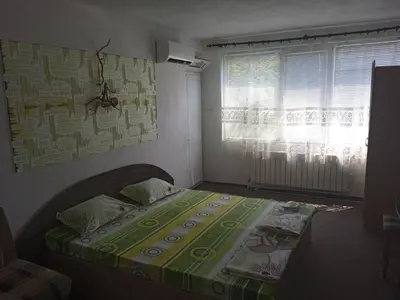 a bedroom with a bed with a green blanket on it at Къща за гости in Primorsko