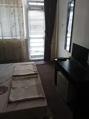 a room with a bed and a desk with a laptop at Къща за гости in Primorsko