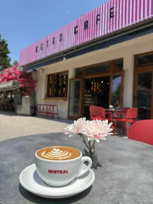 a cup of coffee on a table with a vase of flowers at Hotel Mistral in Nesebar