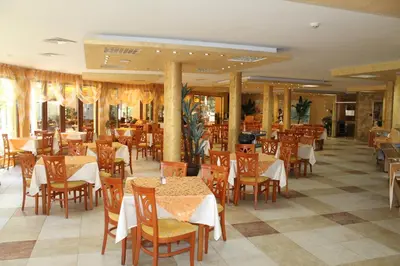 a restaurant with wooden tables and chairs and tables and tablesearcher at Yavor Palace Hotel - All Inclusive in Sunny Beach