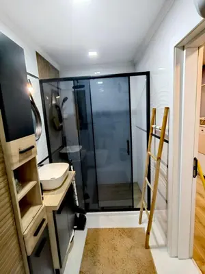 a bathroom with a glass shower and a sink at Апартамент BLUE CREAM in Burgas City