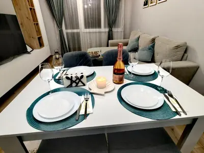 a table with plates and glasses and a bottle of wine at Апартамент BLUE CREAM in Burgas City