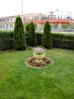 a garden with a large vase with flowers in the grass at Sunny Flower Family Hotel in Sunny Beach