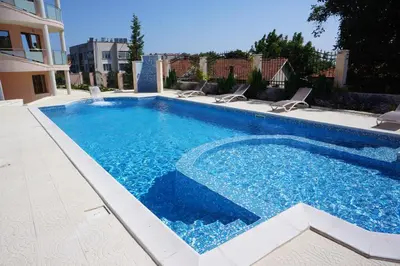 a large swimming pool with chairs and a building at Vello Apartments in Byala