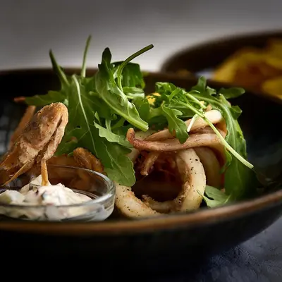 a bowl of food with lettuce and onion rings at The Cliff Lux Apartment Obzor, Burgas, Bulgaria in Obzor