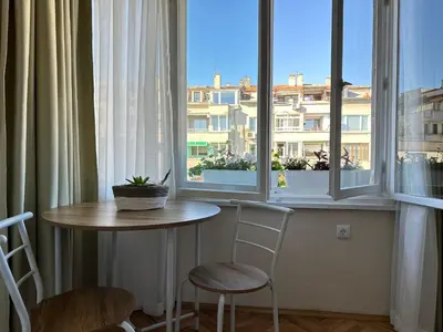 a table and two chairs in a room with a window at Something In French in Burgas City