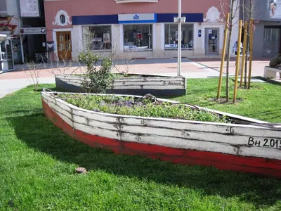 a wooden boat sitting on the grass in front of a building at Apartment Alegria in Varna City