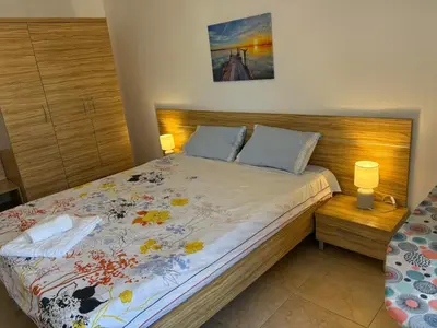 a bedroom with a large bed with a wooden headboard at White Pearl Apartment Sozopol in Sozopol