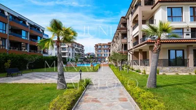 a park with palm trees in front of a building at Zerini Apartment in Burgas City