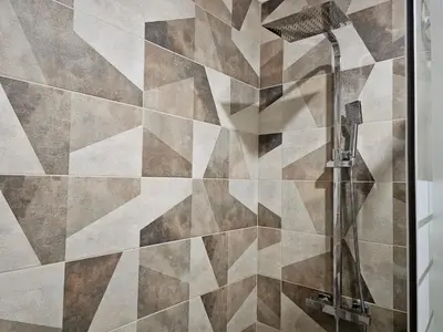 a bathroom with a shower with geometric tiles at Zerini Apartment in Burgas City