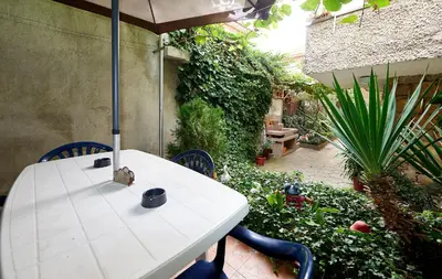 a white table with an umbrella in a garden at Apartment Dora in Pomorie