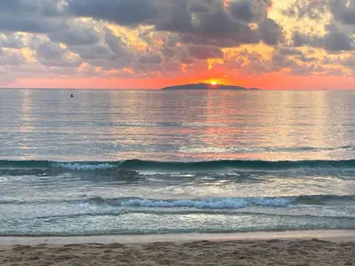 a sunset over the ocean with a beach with waves at Каравана Макси in Chernomorets