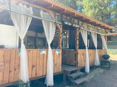a wooden building with white drapes on it at Каравана Макси in Chernomorets