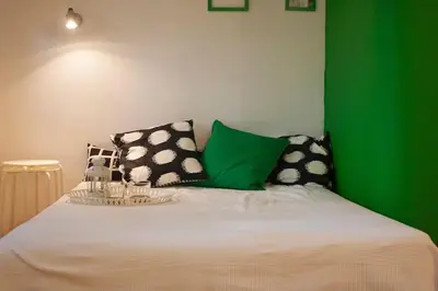 a bed with black and white pillows and a green wall at Varna Heart Studio in Varna City
