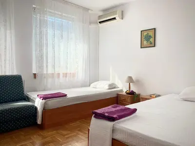 a bedroom with two beds and a chair and a window at Тедис хоум in Burgas City