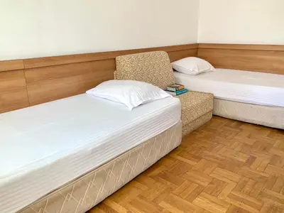 two beds and a chair in a room at Тедис хоум in Burgas City