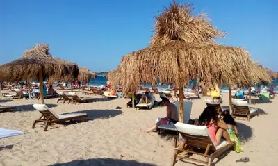 a group of people sitting in chairs under umbrellas on a beach at Apolonia Resort in Sozopol