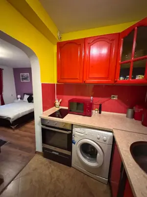 a kitchen with red cabinets and a washing machine at The Central Studio in Burgas City