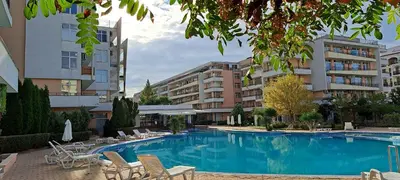 a swimming pool with chairs and tables and buildings at Apartament Amelia in Sunny Beach