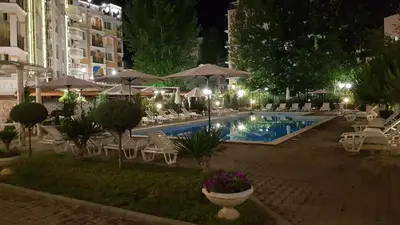an outdoor pool with chairs and umbrellas at night at Vanilla Garden Apartments in Sunny Beach