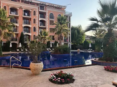 a large building with palm trees and a swimming pool at Cascadas in Ravda