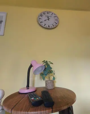 a table with a lamp and a clock on the wall at Tiny House in the center of Varna in Varna City
