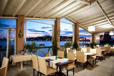 a restaurant with tables and chairs and a view of the water at Poseidon Nessebar Private Apartment in Nesebar