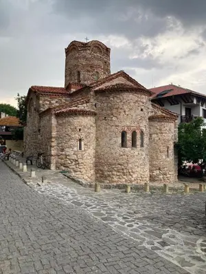 an old stone building with a tower on a street at Sun Wave Apartment near the Sea in Sveti Vlas