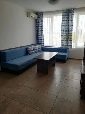 a living room with a blue couch and a table at Apartamenti Zhelezovi in Pomorie