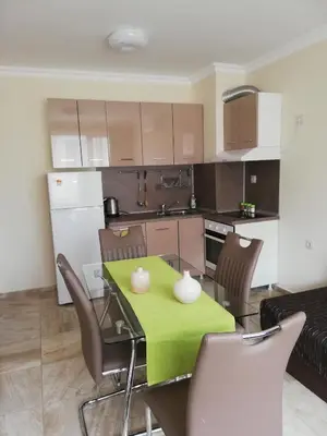 a kitchen and dining room with a green table and chairs at Apartamenti Zhelezovi in Pomorie