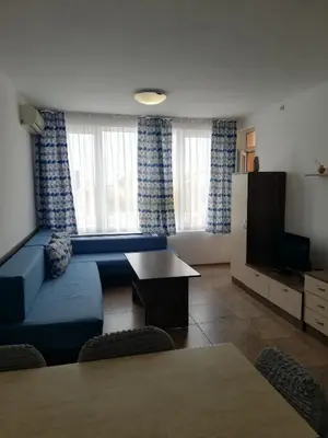a living room with a blue couch and a tv at Apartamenti Zhelezovi in Pomorie