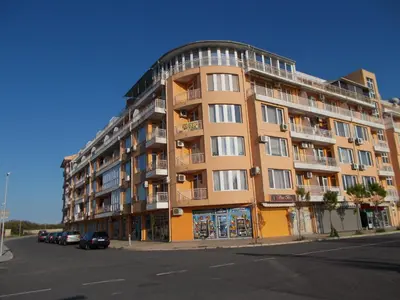 a large apartment building with cars parked in front of it at Apartamenti Zhelezovi in Pomorie