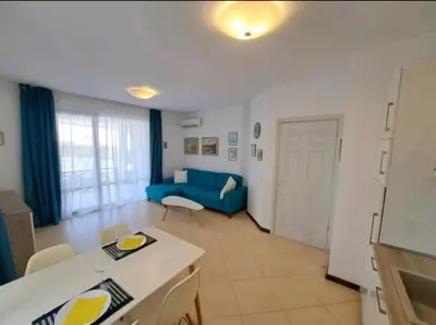 a kitchen and living room with a blue couch at Top Oasis Park Lozenets apartment in Lozenets