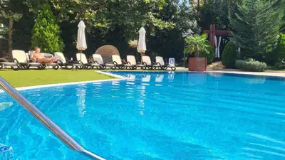 a swimming pool with chairs and umbrellas and a man sitting in a chair at Palma Beach in Harmony Suites 2,3 in Sunny Beach