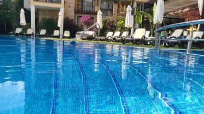 a large blue swimming pool with chairs and umbrellas at Palma Beach in Harmony Suites 2,3 in Sunny Beach