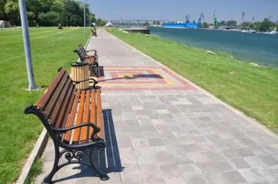 two park benches sitting on a sidewalk near the water at Morava 1 Asparuhovo Beach Holiday House in Varna City