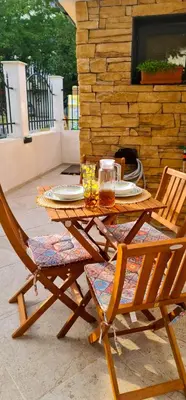 a wooden table and chairs with plates and glasses on it at Morava 1 Asparuhovo Beach Holiday House in Varna City